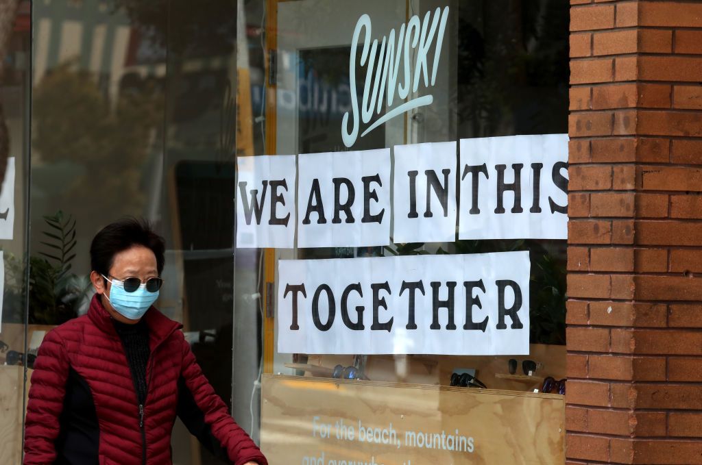 A person walks down the street in San Francisco wearing a mask.