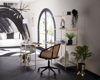 A modern black, white and gold home office with paintstroke wall decor, gold ladder desk and gold shelving unit