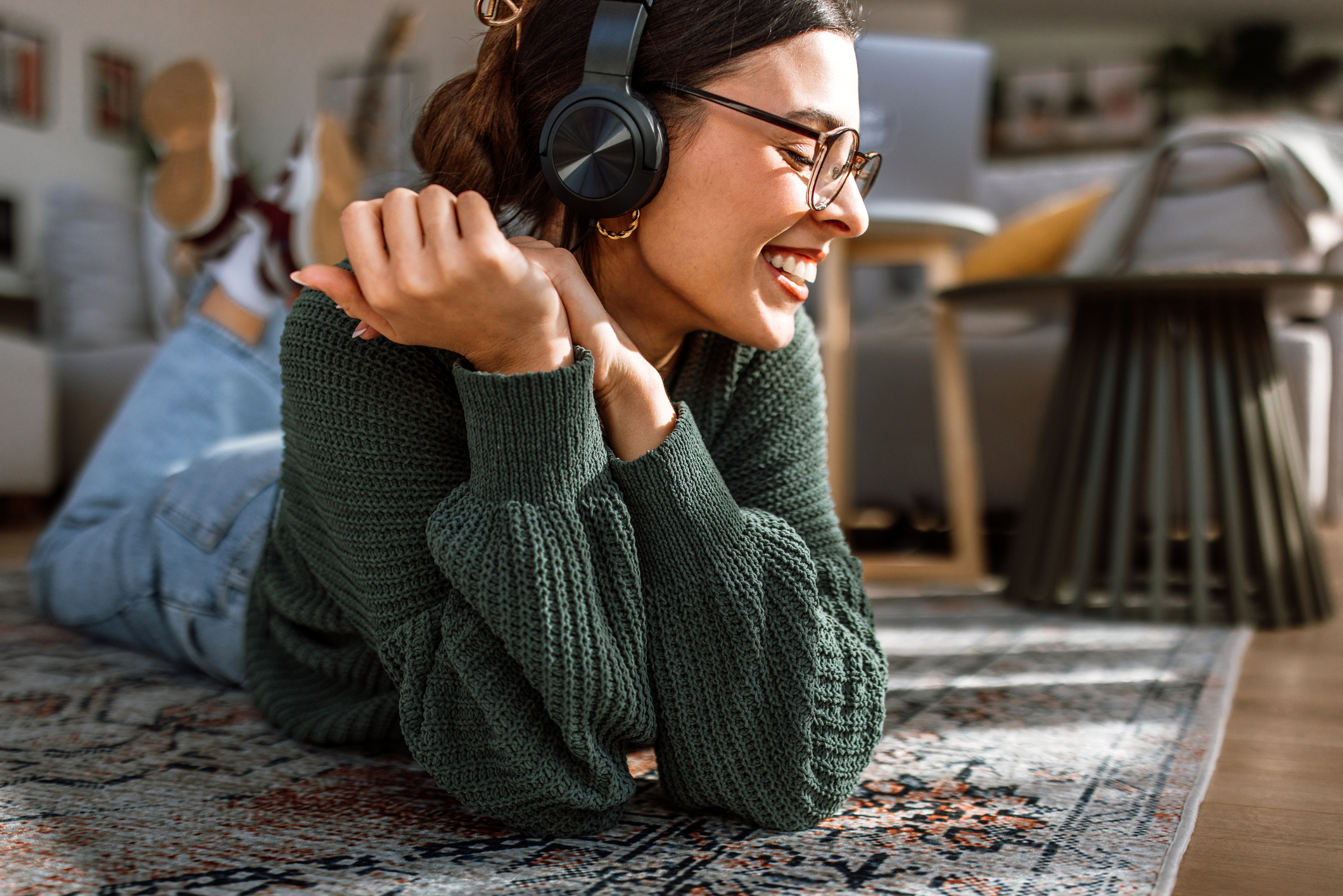 A happy woman lying on the floor listening to music through her headphones.