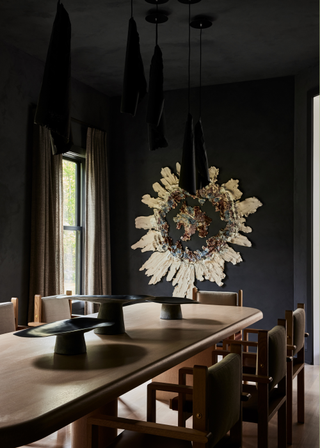 A dining room with dark accents and a long curved wooden dining table