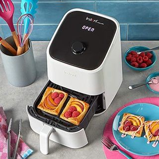White Instant Vortex Mini Air Fryer with open drawer containing pastries next to blue bowls containing ingredients
