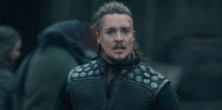 A bloodied Uhtred of Bebbanburg (Alexander Dreymon) in dark clothing, reacting in horror to something he has seen