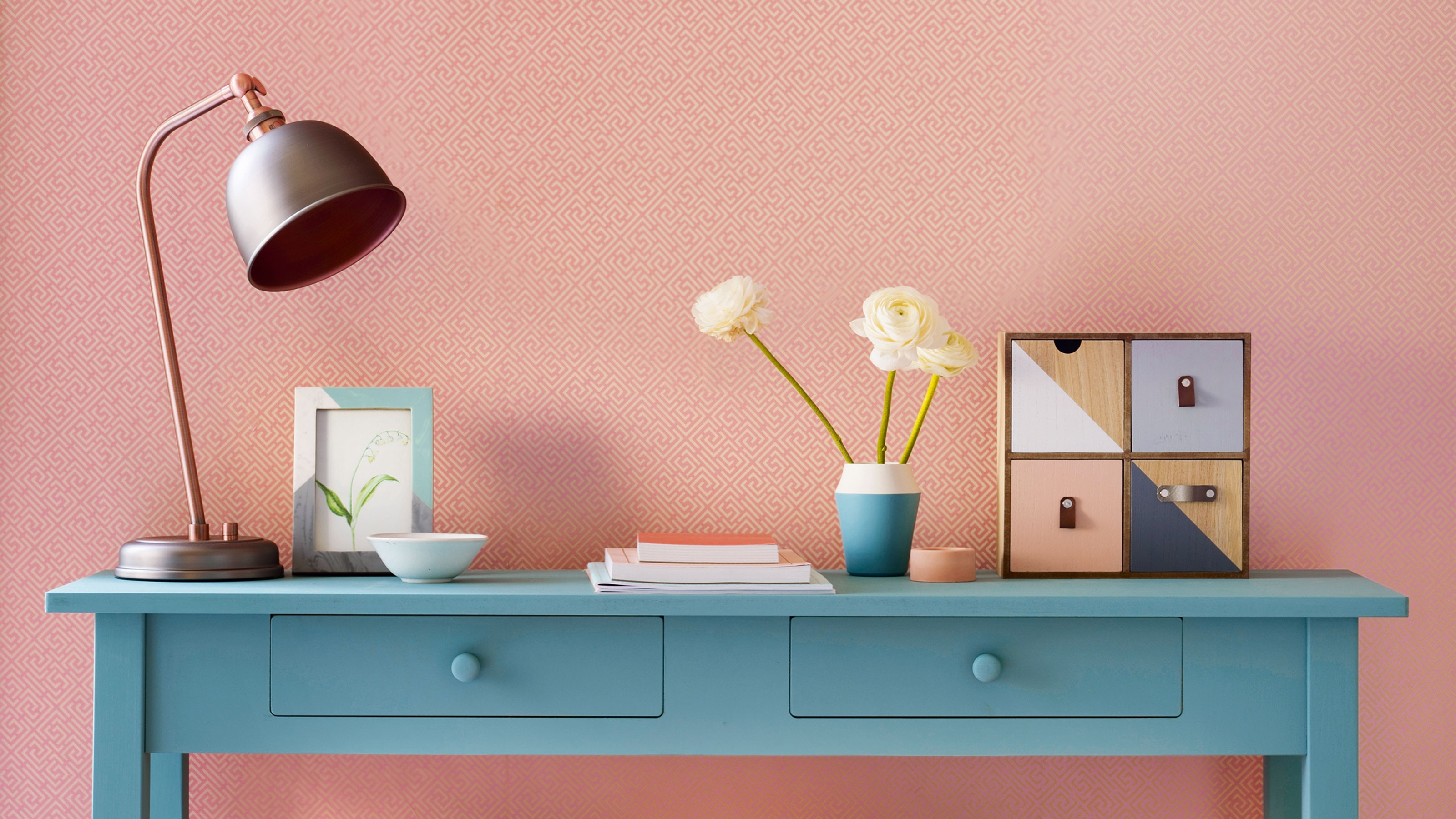 Pink wall with blue console table and table lamp