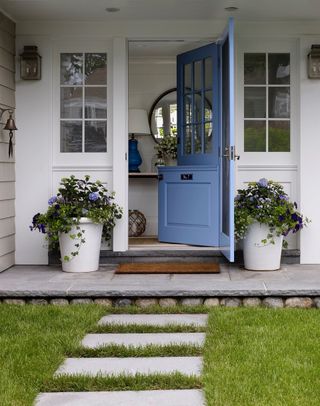 Front porch with Blue dutch doors, potted flowers, grass and patio