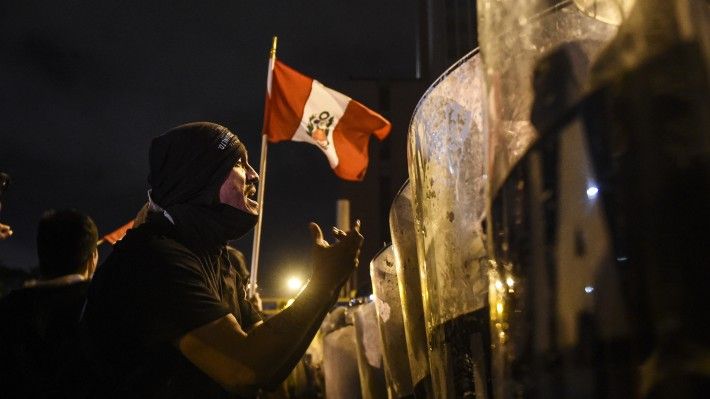 Demonstrators confront riot police during a protest against interim President Manuel Merino