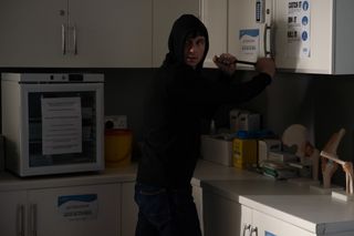 Alex Moore breaking into a cupboard in the surgery with a crowbar