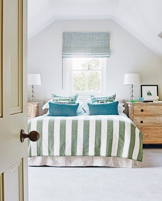 Bedroom with striped bedlinen and blue cushions