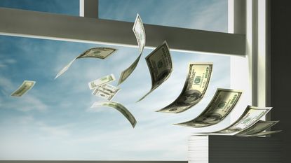 A stock of money is in the process of blowing out an open window.