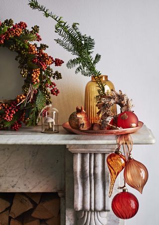 A marble fireplace mantel with Christmas wreath and accessories by John Lewis