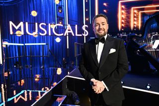 Jason Manford wearing smart suit on stage as he hosts the Big Night of Musicals 2023.