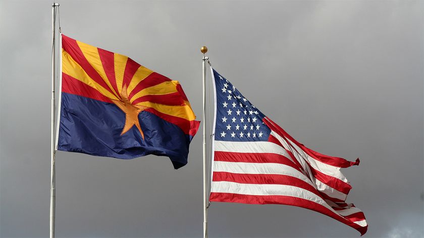 Flags of Arizona and US flying in front of grey storm clouds