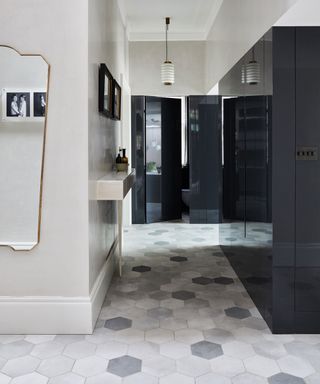 Hallway with grey and white tiled floor and gloss black storage cupboards.