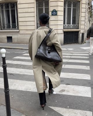 woman carrying a slouchy handbag and wearing a beige trench coat