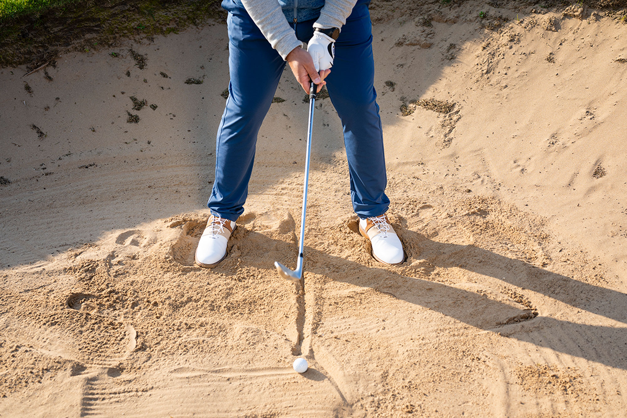 Peter Finch demonstrating a setup change in the fairway bunker, utilising a line in the sand to demonstrate a central ball position and a slightly lower grip on the golf club for added control