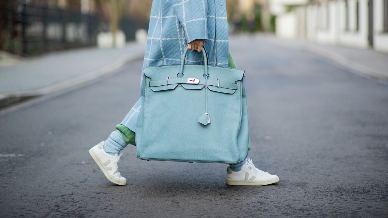 Woman carrying designer bag HERMÈS Birkin travel bag 40 in lightblue 