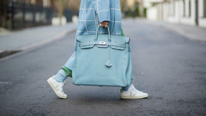 Woman carrying designer bag HERMÈS Birkin travel bag 40 in light blue 