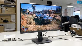 The Asus ROG Strix XG27ACS gaming monitor on a white desk.