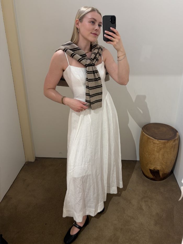 Woman wears white dress, striped cardigan and black ballet flats