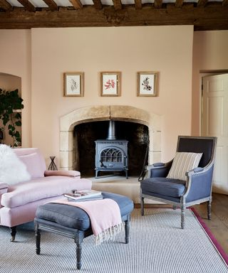 living room with pink walls and woodburner in 12th century Cotswolds country house