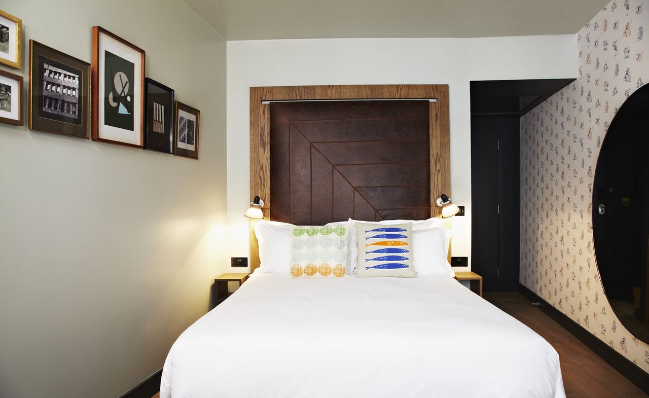 Double bed with patterned cushions and framed pictures on the wall