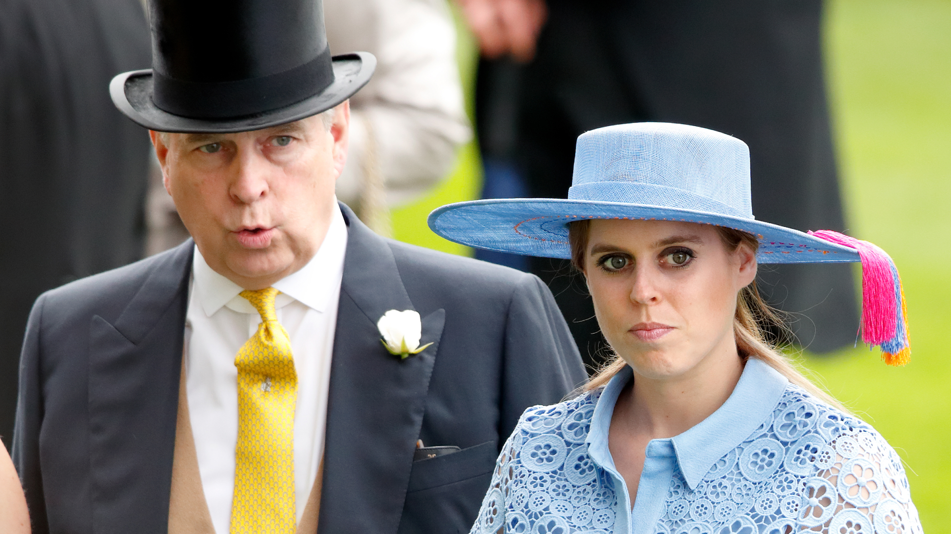 Prince Andrew wears a top hat and suit with a mustard yellow tie and tries to whistle while his daughter, Princess Beatrice, wears a light blue lace shirt dress with a wide-brimmed hat