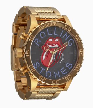 A gold watch with a tongue sticking out of red lips on a black face.