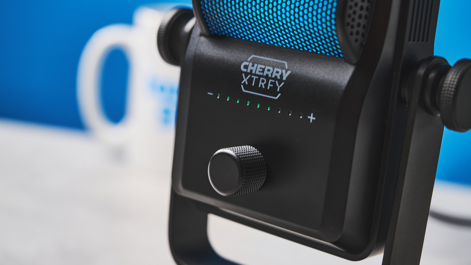 A small retro-inspired microphone with a large RGB sound capsule is photographed against a blue background