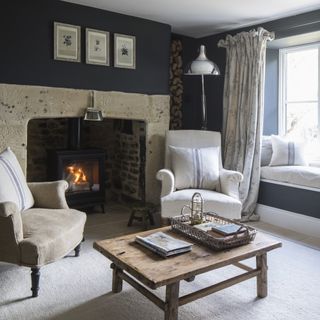 snug living room with large stone fireplace and black painted walls
