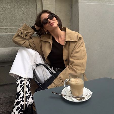 Influencer @maryljean wears cow print pony hair heels with a beige jacket and white jeans.