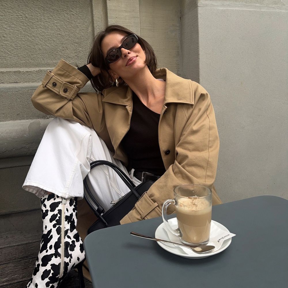 Influencer @maryljean wears cow print pony hair heels with a beige jacket and white jeans.