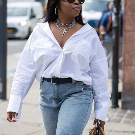 a woman wears a white button-down shirt during Copenhagen Fashion Week