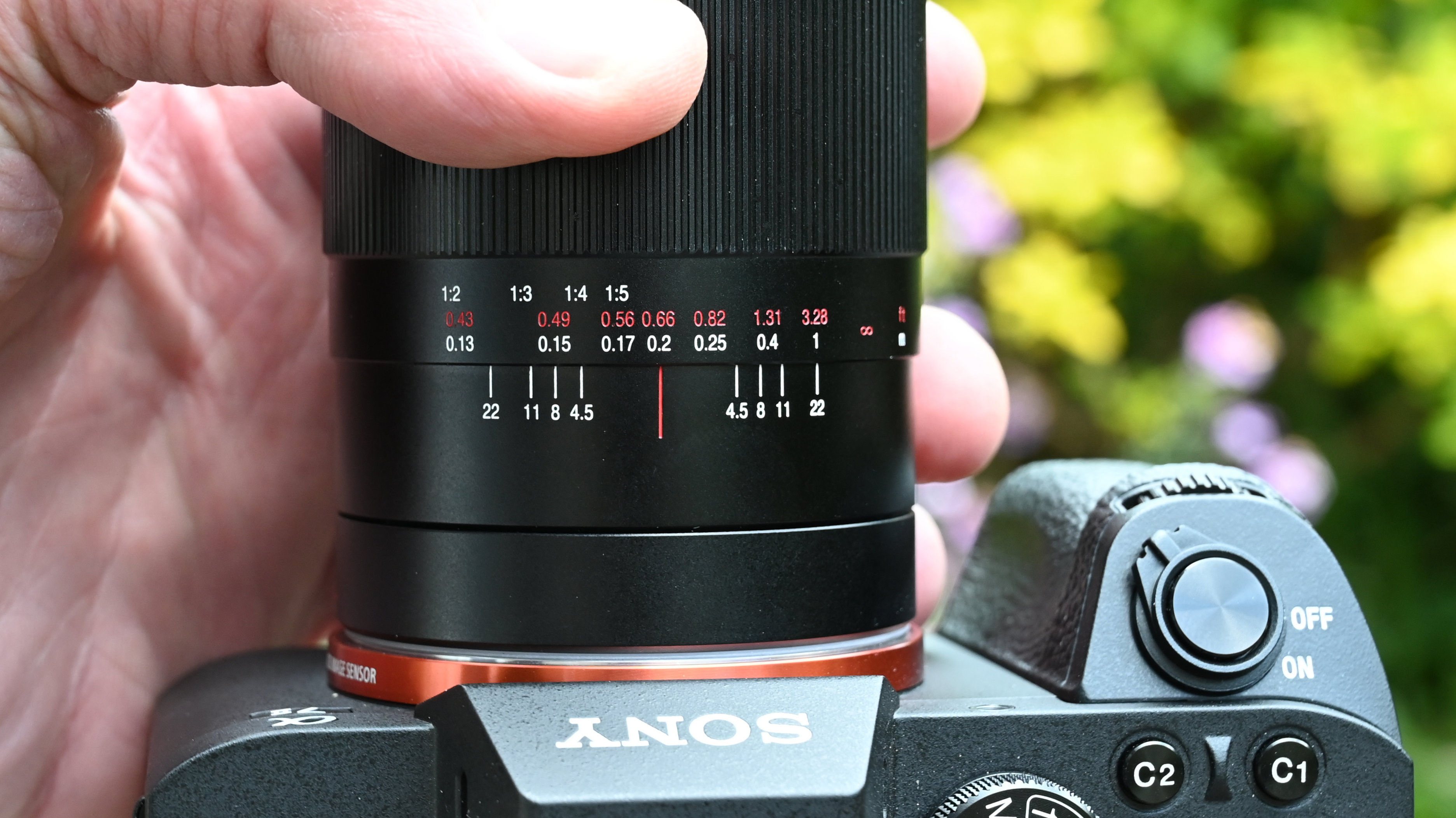 Laowa 15mm f/4.5 0.5x Macro product shot with lens held in hand