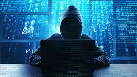 A hacker typing on a computer with binary code