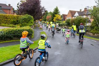 Children and adults ride down a residential road en masse