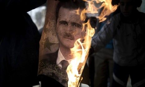 A member of Free Syrian Army burns a portrait of President Bashar al-Assad: Roughly 6,000 people have been killed during Syria&amp;#039;s nearly-year-long uprising.