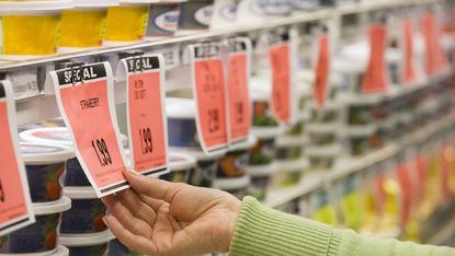 Hand holding a sale price tag in a supermarket aisle