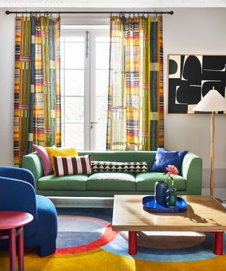 colourful living room with green sofa, patterned curtains and abstract rug and artwork