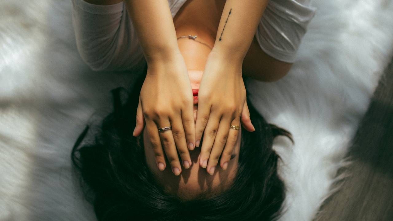 Women lying upside down on a mattress with her hands over her face, sleep and wellness tips