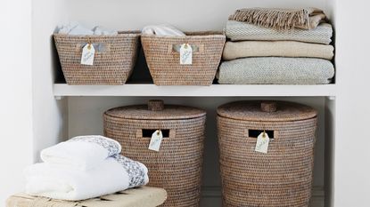 Linen cupboard with folded towels and labelled storage baskets