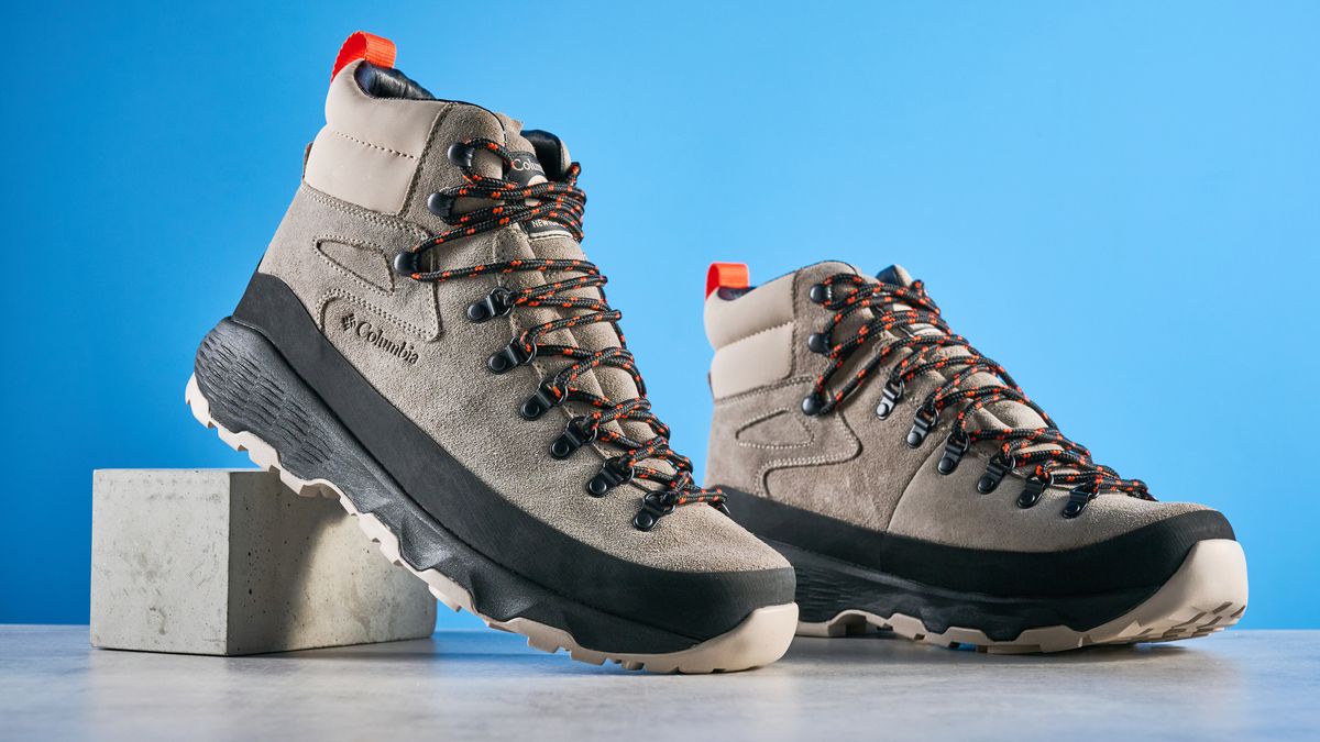 The Columbia Newton Alpine boots on a stone surface with a blue background