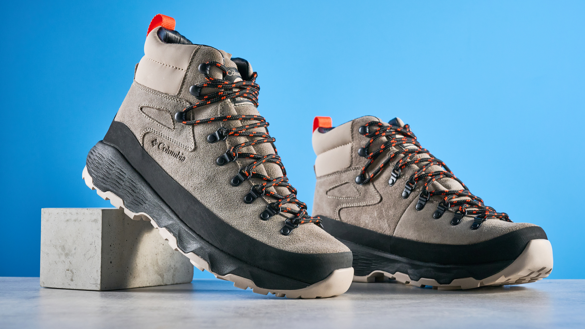 The Columbia Newton Alpine boots on a stone surface with a blue background