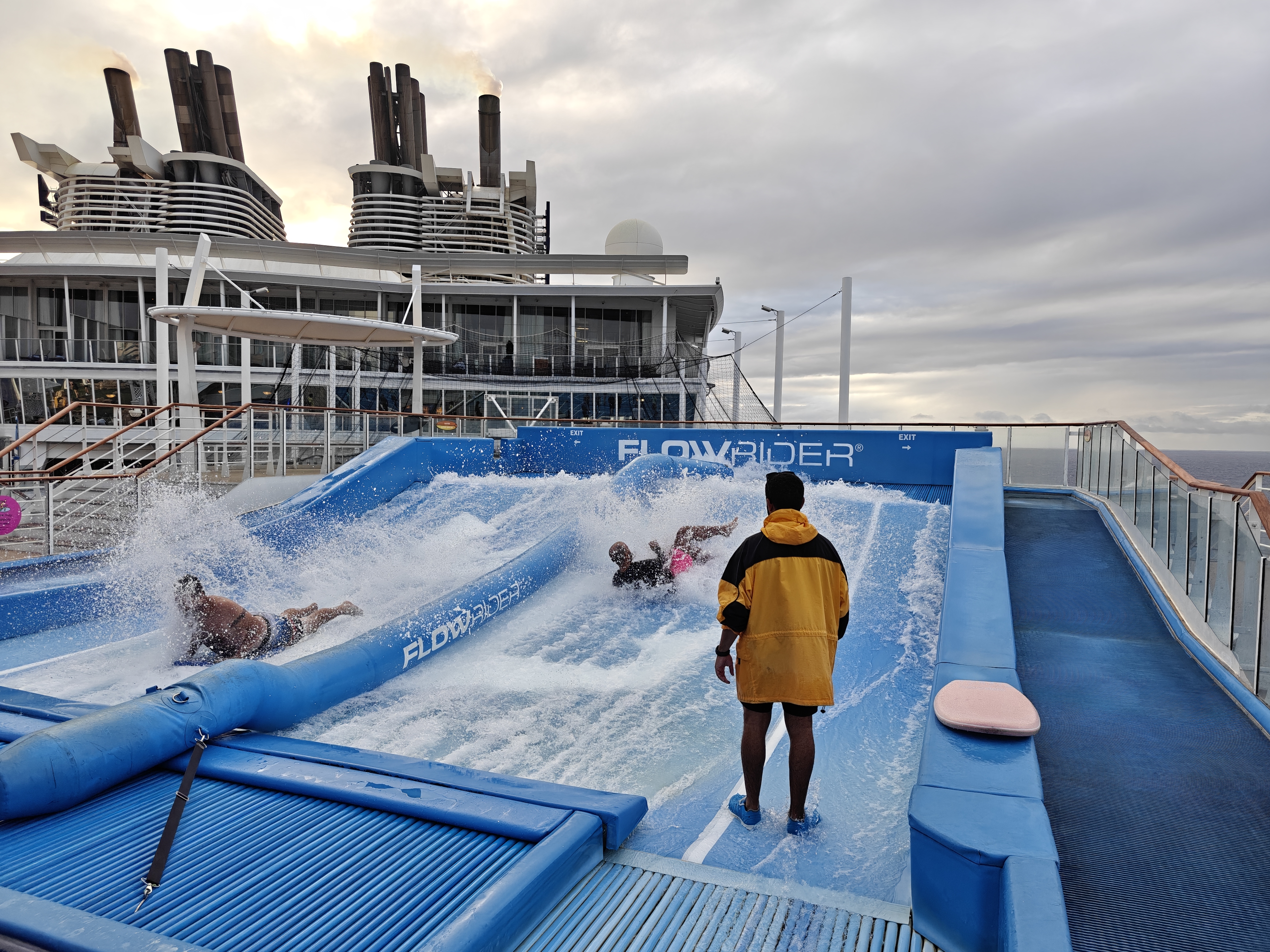 Two men on boogie boards wipe out while riding Flow Rider on the Royal Caribbean cruise during the day