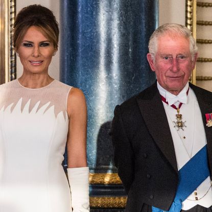 Melania Trump wears a white sleeveless dress with bouffant hair while King Charles wears a tuxedo