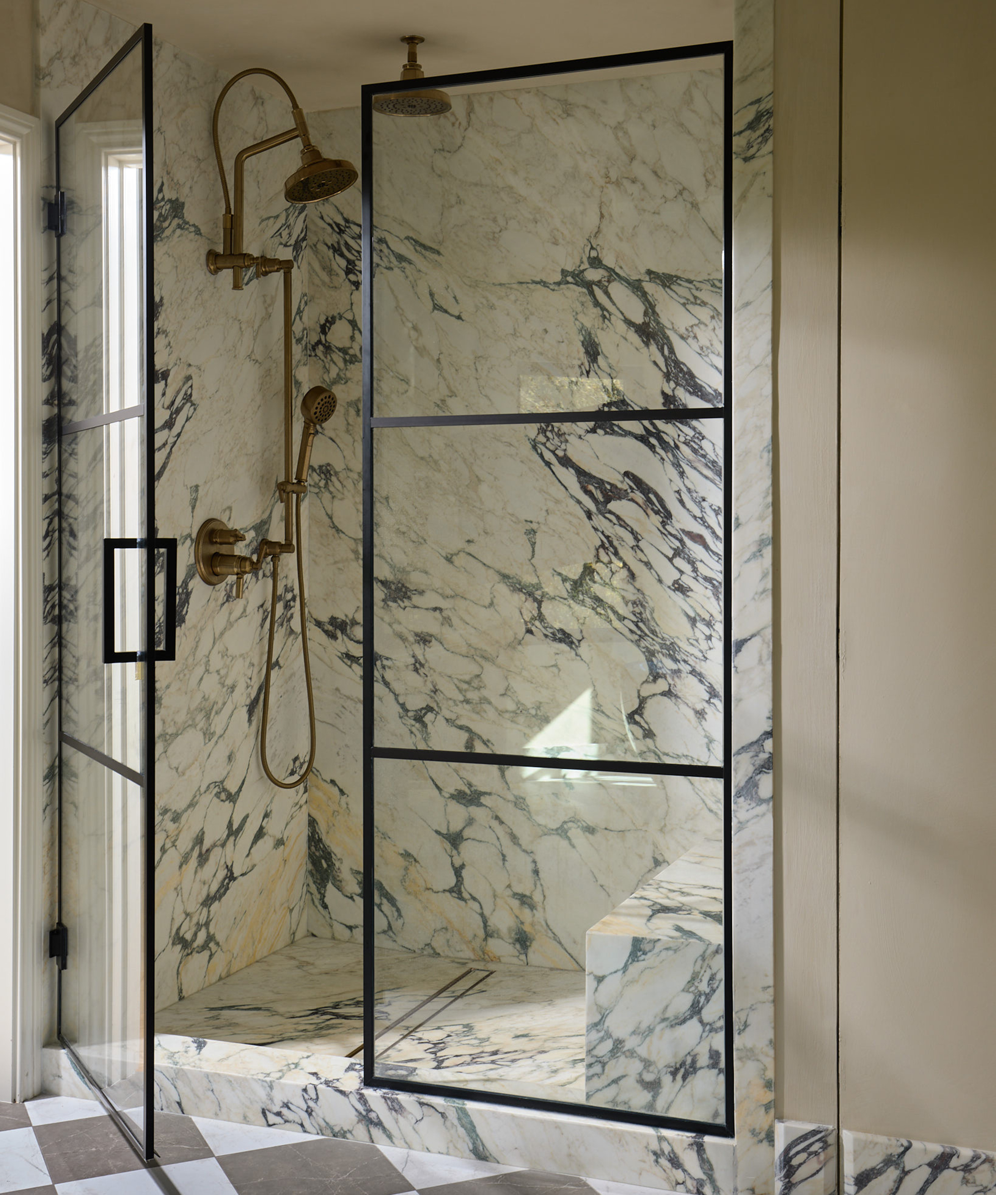 walk in shower with deep veined marble floor and wall