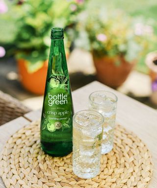 Bottle of drink beside two tall glasses outside bottlegreen