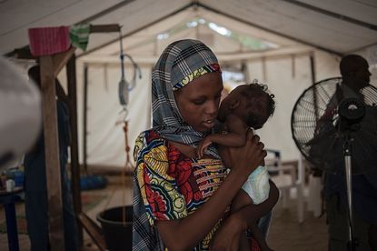 A woman in northeastern Nigeria holds her malnourished baby.