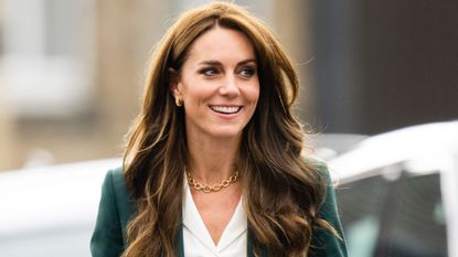 Catherine, Princess of Wales whilst visiting Leeds on September 26, 2023, in a green Burberry wool suit, white shirt and gold jewellery, smiling and looking away from the camera 
