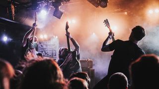 We Lost The Sea guitarists Matt Kelly, Mark Owen and Matt Harvey raise their guitars in the air onstage