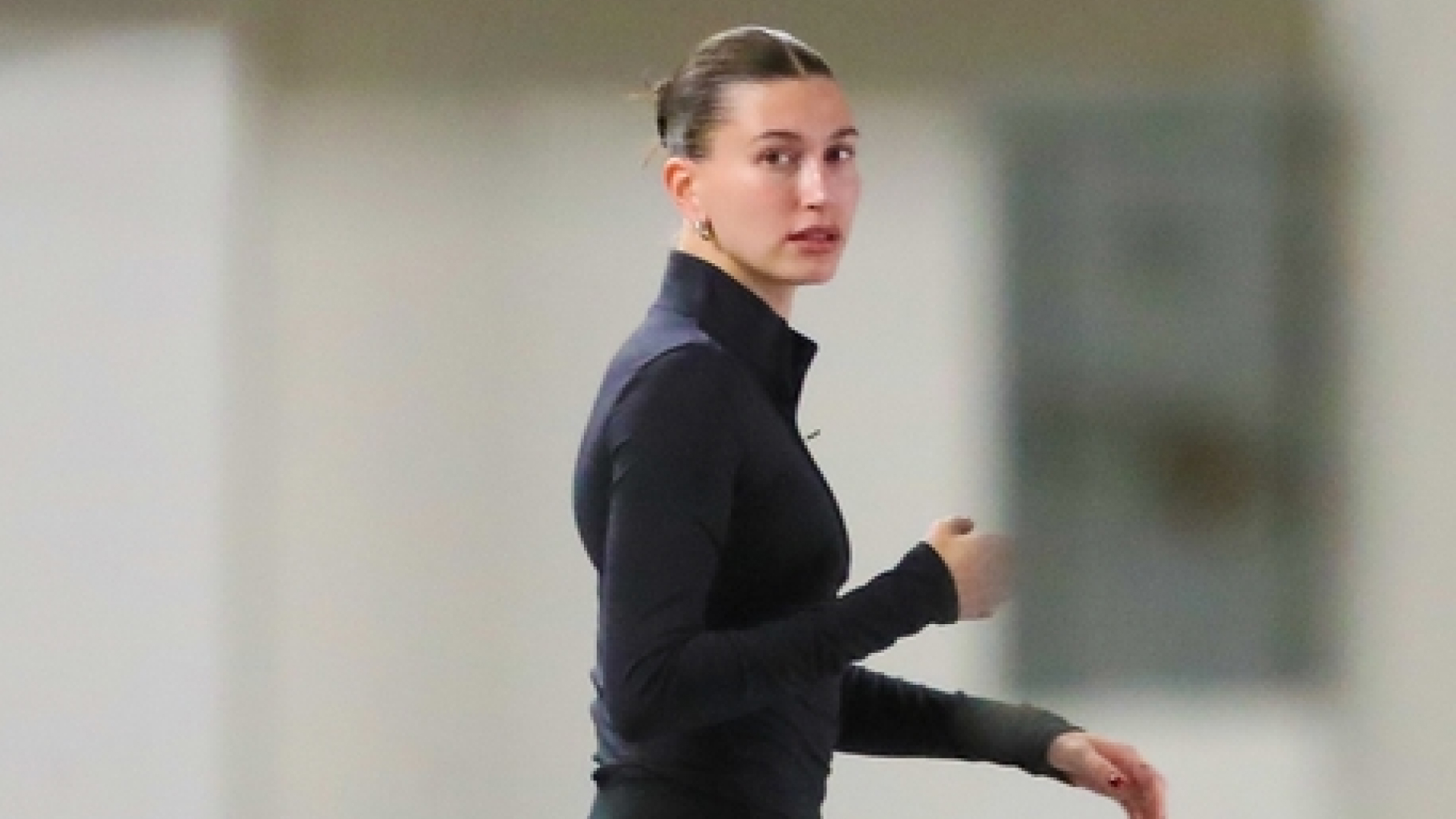 Hailey Bieber walks in Los Angeles wearing a black zip-up jacket and flare leggings