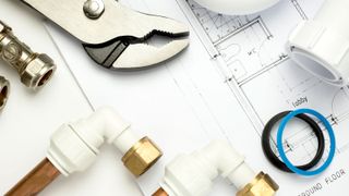 Close of of plumbing tools, fitting and pipes on top of architects plans